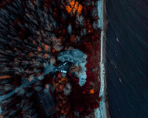 Aerial shot of a house in a forest next to a lake