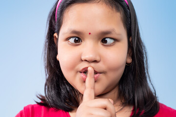 Fototapeta premium Close Up Of girl With Finger On Lips and making a teasing face