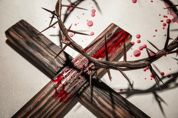 Crown of thorns, wooden cross and blood drops on light background. Jesus Christ's sacrifice and atonement of our sins