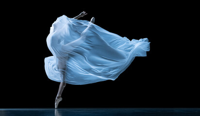 Graceful classic ballerina dancing with weightless fabric isolated on black studio background in...