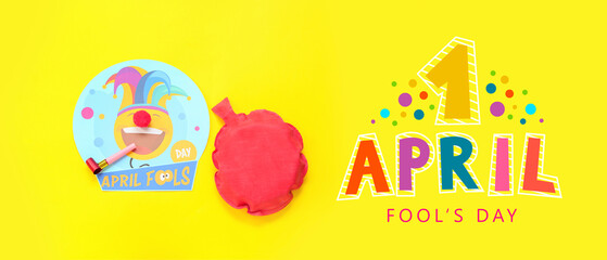 Whoopee cushion, paper card with clown, party whistle and text 1 APRIL, FOOL'S DAY on yellow background
