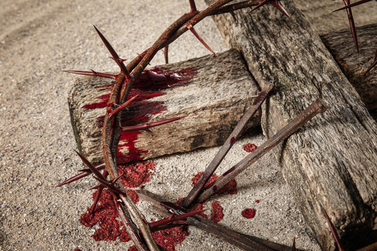 Crown of thorns, wooden cross, nails and blood drops on sand. Jesus Christ's sacrifice and atonement of our sins