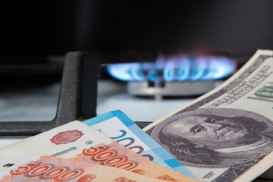 American dollars and Russian rubles against the background of burning gas. Banknotes of Russian rubles and US dollars. The concept of a trade war between the USA and Russia