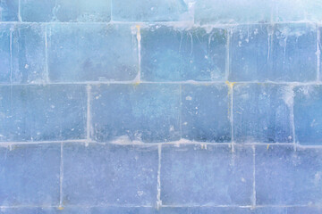 The textured surface of a translucent large ice wall made of large bricks.