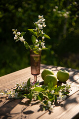 Green apples and flowers on a wooden table. Beautiful shadows