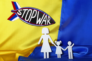 Paper figure of family and drawn missile on flag of Ukraine. Stop war
