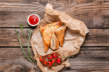 Tasty Uzbek samsa and tomato sauce on wooden background