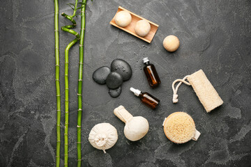 Spa composition with bathing supplies, essential oil and stones on dark background
