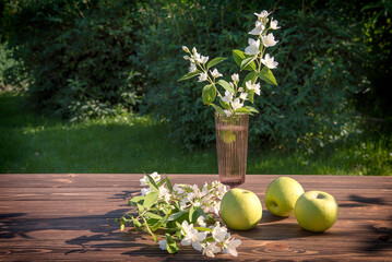 Green apples and flowers on a wooden table