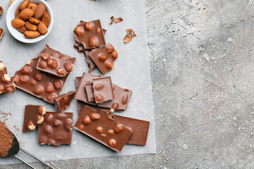 Pieces of tasty chocolate with nuts on grunge background