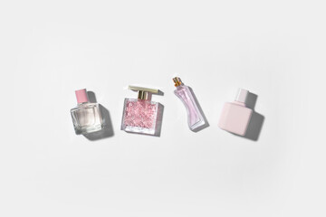 Bottles of different perfumes on light background, top view