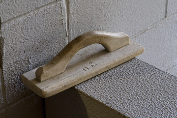 Wooden finishing trowel tool on a concrete wall