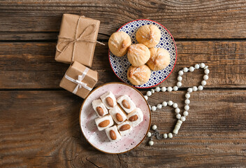 Tasty Eastern sweets with gifts and tasbih on wooden background