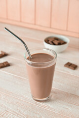 Glass of delicious chocolate milk on wooden background