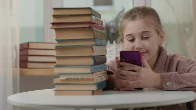 girl with a phone in her hands near a stack of books