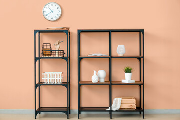Shelves with stylish decor near color wall