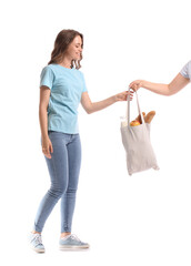 Young woman taking eco bag with food and drink on white background