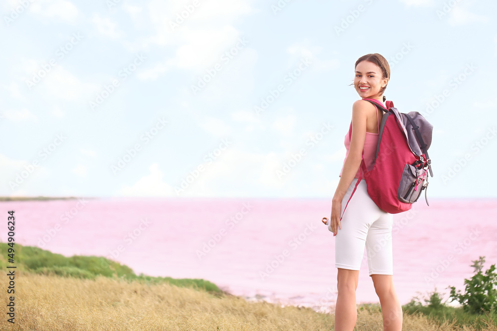 Sticker Young tourist with backpack near pink lake