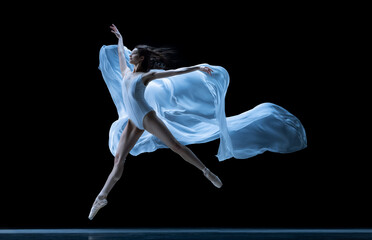 Graceful classic ballerina dancing with weightless fabric isolated on black studio background in...