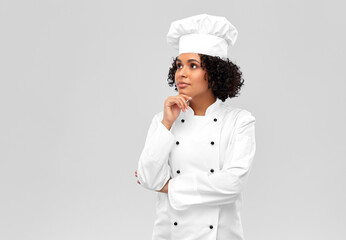 cooking, culinary and people concept - thinking female chef in white toque and jacket over grey...