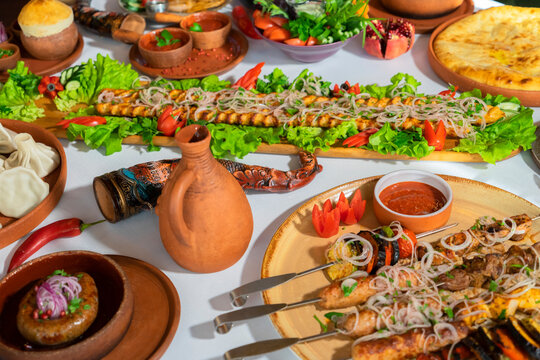Georgian cuisine. A large laid table of different dishes for the whole family on a day off. Kebab, Lula, Lavash, Suluguni cheese, Khachipuri, Khinkali. background image