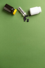 Bottles of activated carbon pills on green background