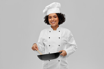 food cooking, culinary and people concept - happy smiling female chef with frying pan over grey...