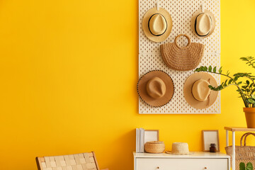 Pegboard with hats and bag hanging on yellow wall