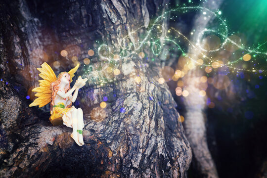 image of magical little fairy in the forest sitting on the tree