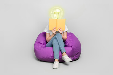 Female body of model with bright electric bulb instead head read book sit bean bag isolated on grey color background modern design learn concept - obrazy, fototapety, plakaty