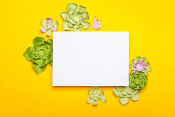 Beautiful handmade paper flowers with blank paper sheet on orange background