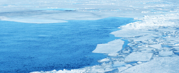 Breaking spring ice floe at the sea, panoramic view. Natural ice blocks, sea ice during winter weather