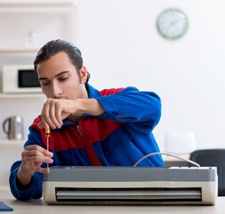 Young repairman repairing air-conditioner at warranty center