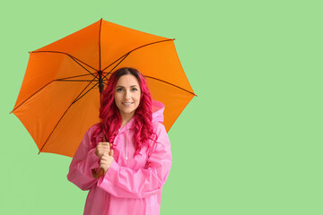 Beautiful woman in raincoat and with umbrella on color background