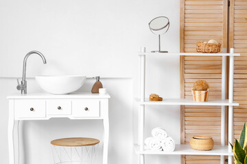 Interior of light bathroom with sink, shelving unit and supplies
