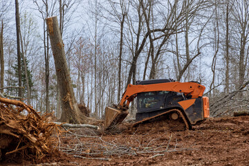 Tractor working the with preparing land for housing new complex property clearing tree root