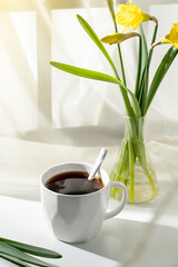 a cup of tea on a light background with a bouquet of daffodils, cover 