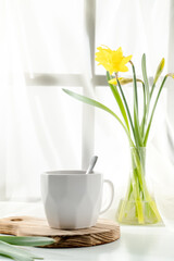 a cup of tea on a light background with a bouquet of daffodils, cover 