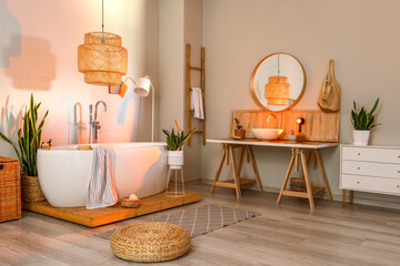 Interior of modern bathroom with table, sink and houseplants in evening