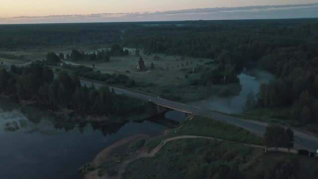 An early foggy morning in the countryside outside the city. Lonely road, bridge, church, fog, forest around