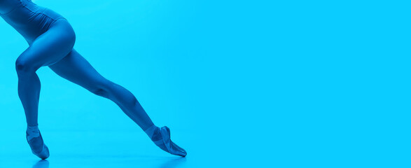 Flyer. Close-up ballerina's legs in pointe shoes isolated on navy color studio background in neon....