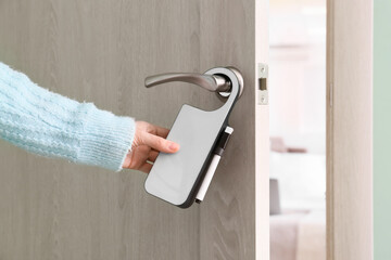 Woman with door hanger in hotel room, closeup