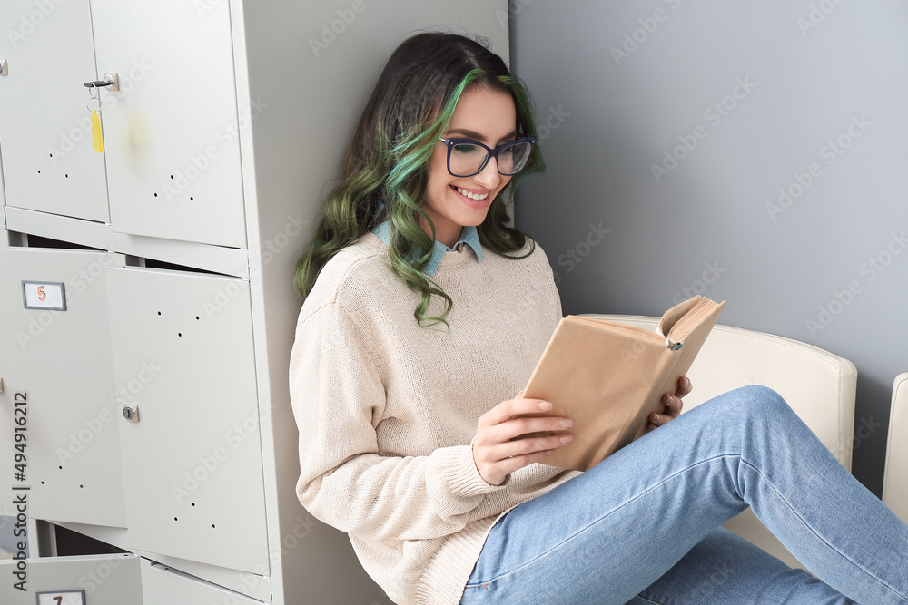 Canvas Prints Beautiful female student reading book while sitting near locker at the university