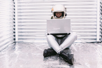 Black astronaut browsing laptop in spaceship