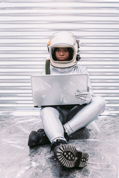 Black astronaut browsing laptop in spaceship
