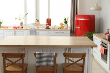 Stylish dining table, counters and new refrigerator in kitchen