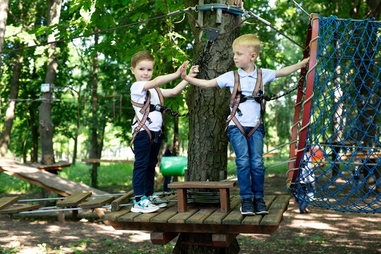 Two little friends say hello while passing the tests in the rope park. - Powered by Adobe