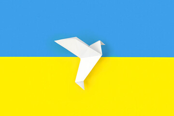 One white origami paper dove on colors of flag of Ukraine. The concept of peace between two states....