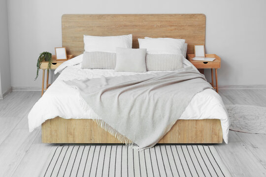 Comfortable bed and nightstands near light wall