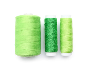 Green sewing thread spools on white background